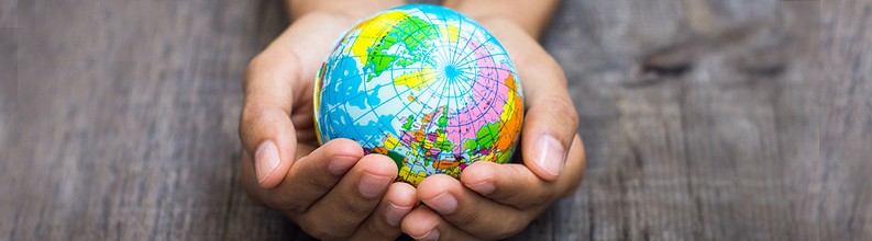 Roke držijo majhen barvit globus, ki simbolizira skrb za svet oziroma globalno odgovornost.