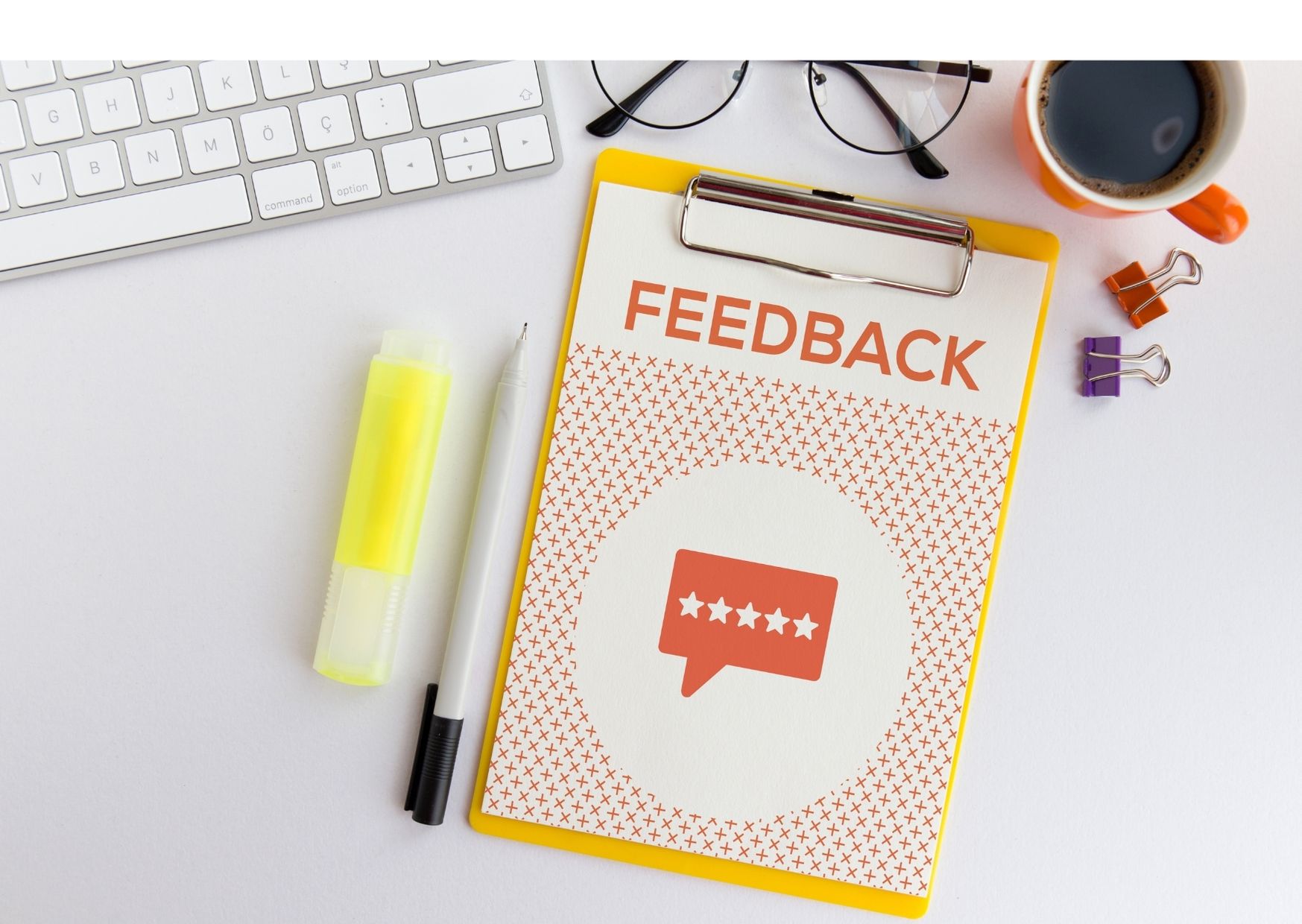 Na mizi z delovnimi pripomočki je obrazec z napisom ‘Feedback’, kar simbolizira pomen povratnih informacij, ocenjevanja in nenehnega izboljševanja v poslovnem okolju