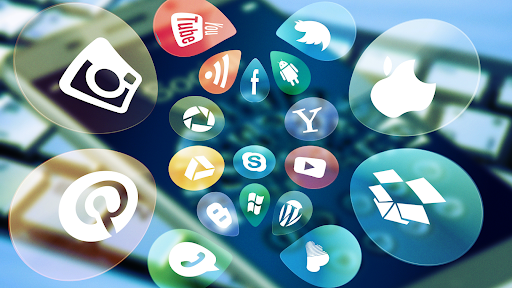 Različne ikone družbenih omrežij in digitalnih platform na zaslonu predstavljajo digitalni marketing, spletno komunikacijo in uporabo tehnologije za povezovanje z uporabniki.